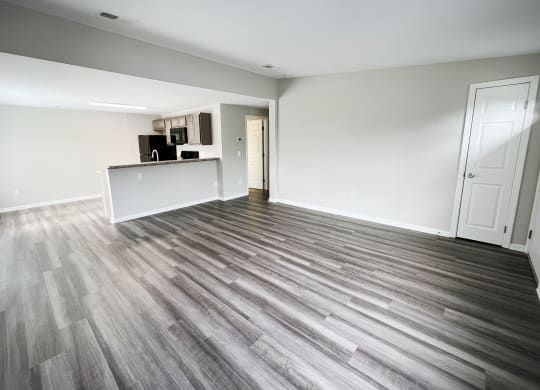 an empty living room with a kitchen in the background  at Woodhills Apartments, West Carrollton, Ohio
