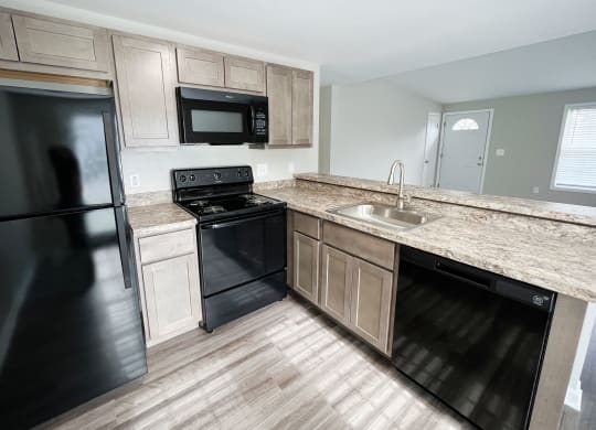 a kitchen with black appliances and wooden cabinets  at Woodhills Apartments, West Carrollton, OH, 45449