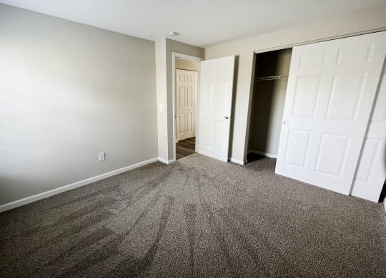a bedroom with gray carpet and a closet with a white door  at Woodhills Apartments, West Carrollton, 45449