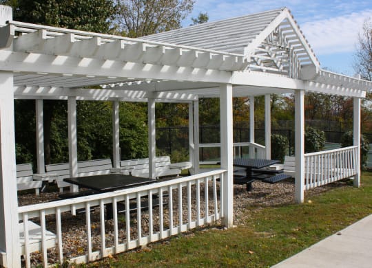 a white pergola with a table and benches in a garden  at Knobs Pointe Apartments, New Albany
