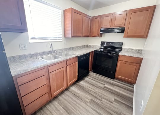 an empty kitchen with wooden cabinets and black appliances at The Villas at Kingswood, West Chester, OH