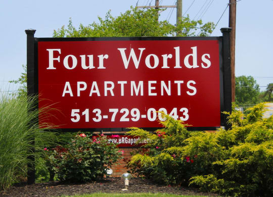 a red sign for four worlds apartments in front of plants  at Four Worlds Apartments, Cincinnati, Ohio