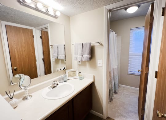 a bathroom with a sink and a mirror and a shower at The Vinings Apartments, Cincinnati, Ohio
