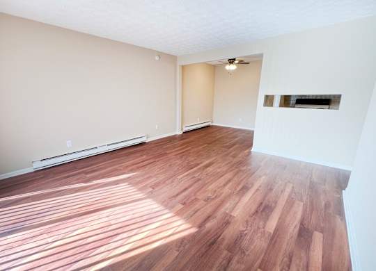 the living room and dining room of an empty house with wood flooring at Concord Woods Apartments, Milford, OH 45150