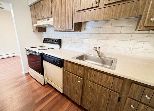 a kitchen with white appliances and wooden cabinets at Concord Woods Apartments, Milford