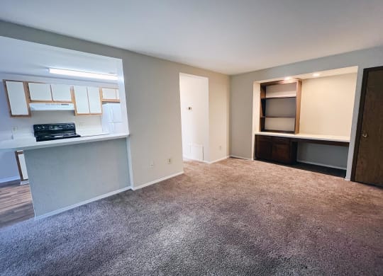 an empty living room with a kitchen in the background  at Woodhills Apartments, West Carrollton, Ohio