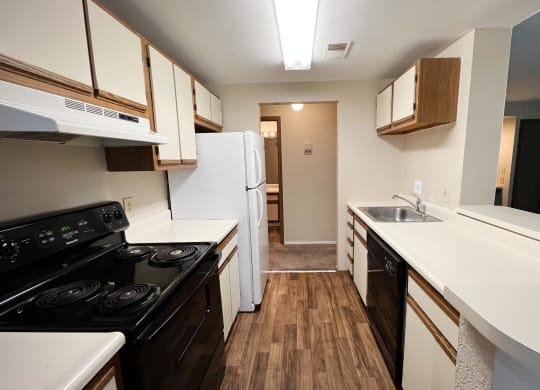 a kitchen with white countertops and a black stove top oven  at Woodhills Apartments, West Carrollton