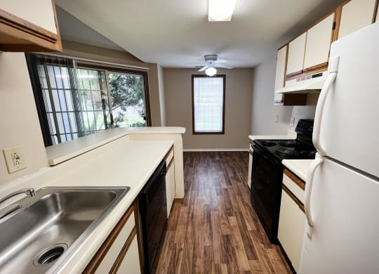 a small kitchen with white countertops and black appliances  at Woodhills Apartments, Ohio