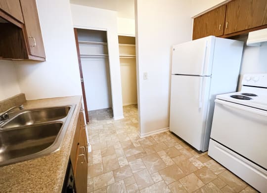 a kitchen with a white refrigerator freezer next to a white stove top oven  at Four Worlds Apartments, Cincinnati, OH