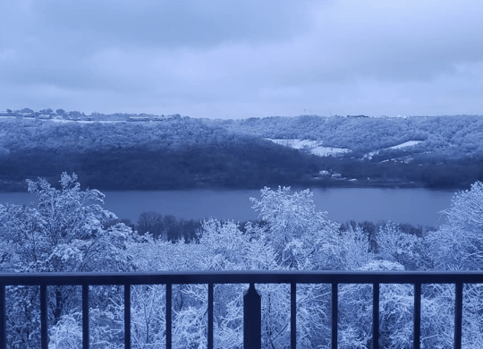 a balcony overlooking a lake and trees in the snow at Indian Lookout Apartments, Cincinnati, OH
