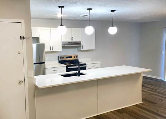 A kitchen with white cabinets and a white island.