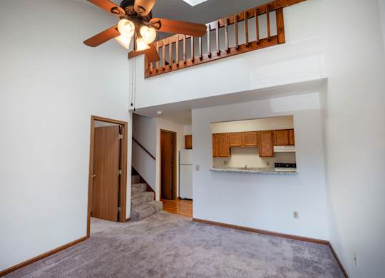 A room with a ceiling fan and a staircase leading to the upper floor.