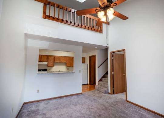 A room with a ceiling fan and a staircase.