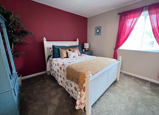 A bedroom with a white bed and a red curtain.