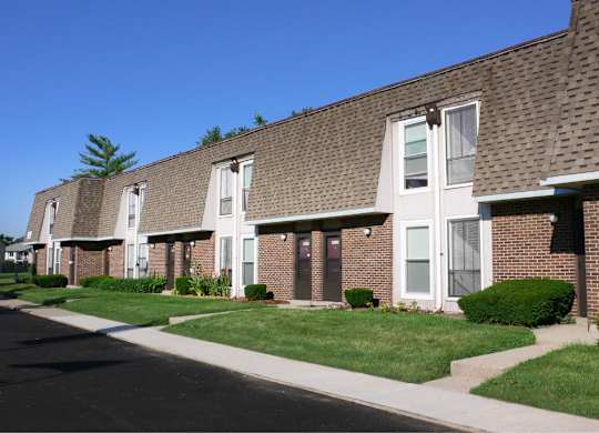 A long row of houses with green lawns and white windows.