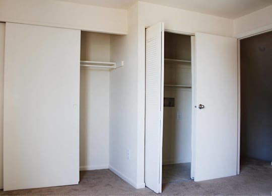 A white closet with a door open to a hallway.