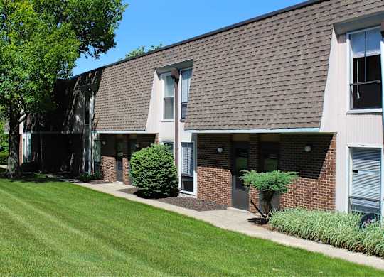 A building with a brown roof and a green lawn in front.