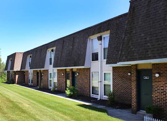 A long building with a green door and a white picket fence.