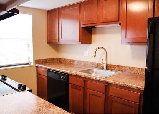 A kitchen with brown cabinets and a black refrigerator.