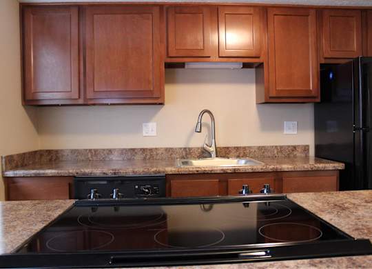 A kitchen with a black stove top oven and wooden cabinets.