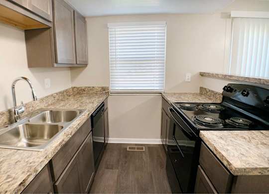 A kitchen with a sink, stove, and cabinets.