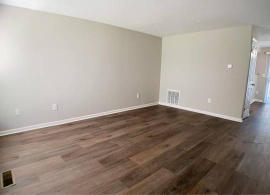 A room with wooden flooring and a window on the left side.