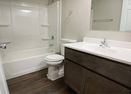 A white toilet sits in a bathroom next to a bathtub.