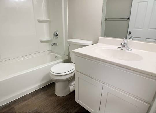 A white bathroom with a toilet, sink, and bathtub.
