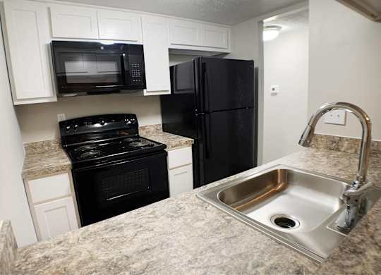A kitchen with black appliances and a granite countertop.