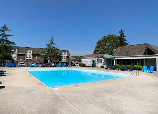 A large swimming pool surrounded by trees and a building.