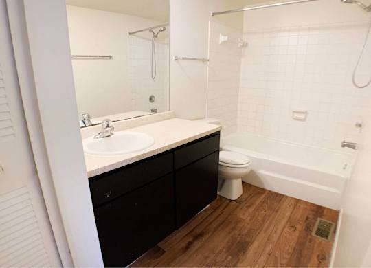 A white bathroom with a wooden floor and a white toilet.