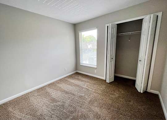 A room with a carpeted floor and a doorway leading to another room.