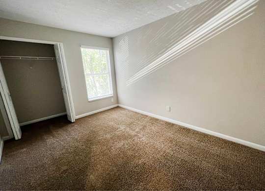 A room with brown carpet and a window.
