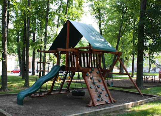 A playground with a green slide and a wooden structure.