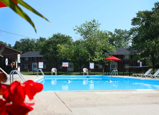 a swimming pool with chairs and a red umbrella at Sharondale Woods Apartments, Ohio