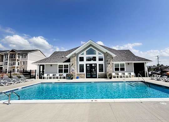 Swimming pool with clubhouse and white lounge chairs at The Meridian on 32 Apartments, Batavia, Ohio