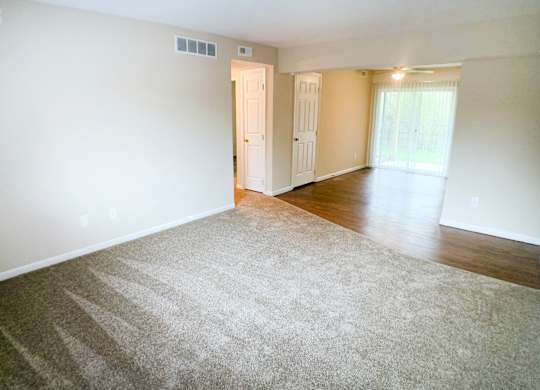 A room with a carpeted floor and a door leading to another room.