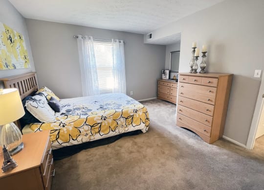a bedroom with a bed and a dresser in itat Revere Village Apartments, Centerville