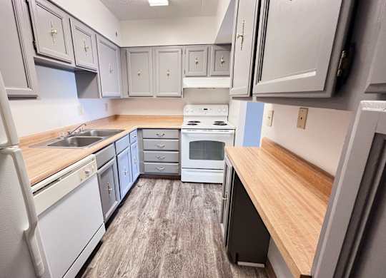 A kitchen with white appliances and wooden countertops.