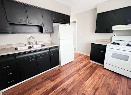 A kitchen with black cabinets and a white refrigerator.