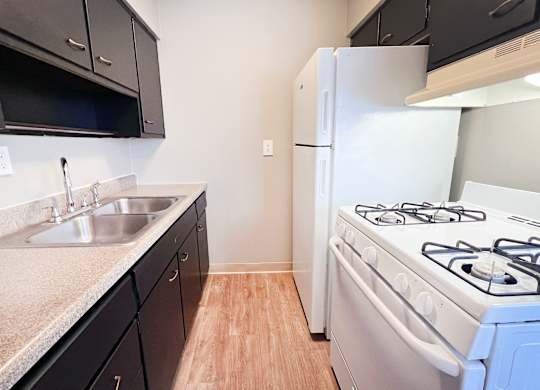 A kitchen with a white stove and black cabinets.