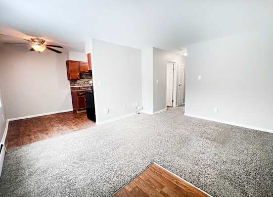 A spacious living room with a grey carpet and a ceiling fan.