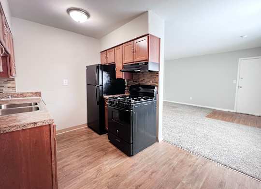 A kitchen with black appliances and wooden cabinets.