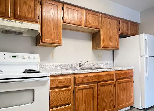 A kitchen with wooden cabinets and a white oven.