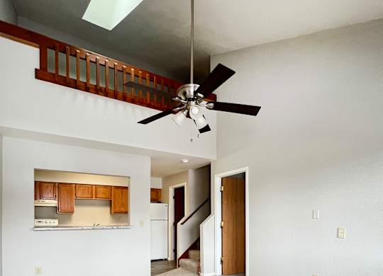 A room with a ceiling fan and a staircase.