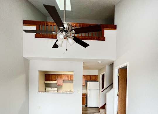 A room with a ceiling fan and carpeted floor.