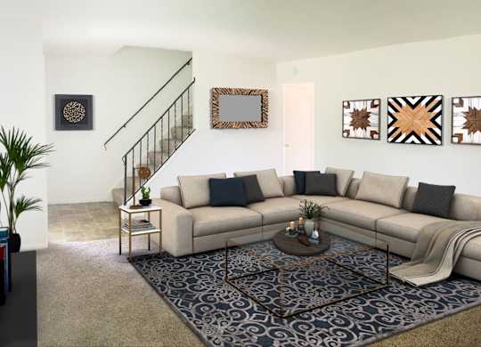 A living room with a beige couch, a coffee table, and a staircase.