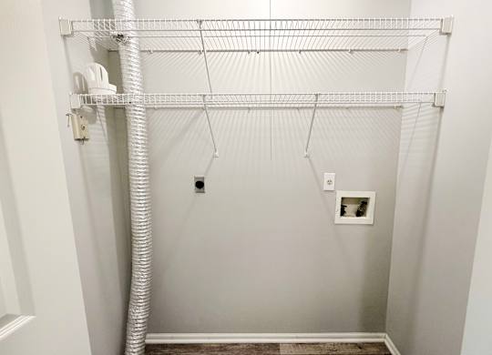 A white closet with a white pipe and a white shelf.