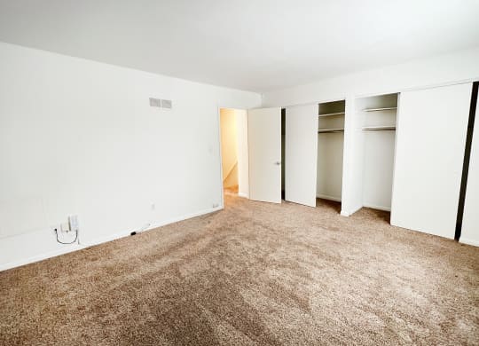 an empty room with white walls and carpet and closet doors at Walnut Creek Townhomes, OH 45236