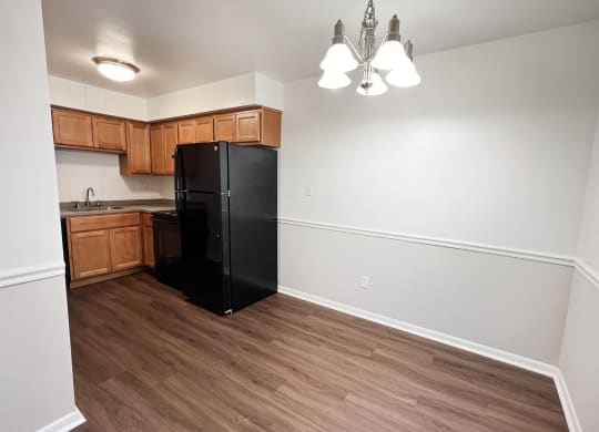 an empty kitchen with a black refrigerator and wooden cabinets at Walnut Creek Townhomes, Cincinnati